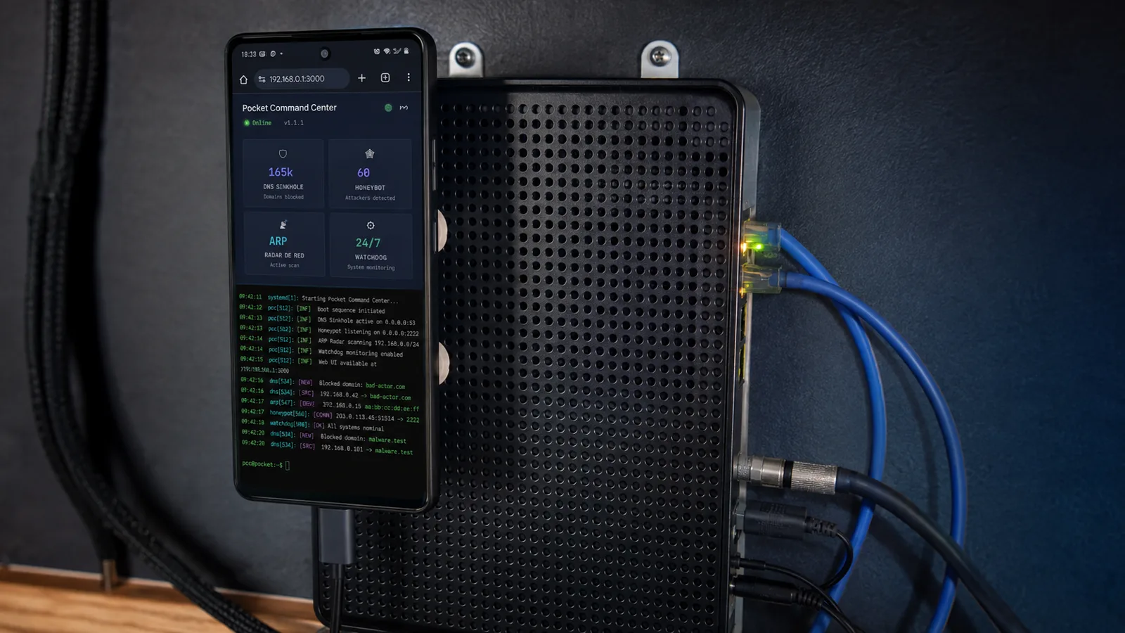 Pocket Command Center corriendo en un teléfono conectado por USB-C junto al módem: tablero con DNS Sinkhole en 165k dominios, honeypot, radar ARP y watchdog, con la bitácora en vivo